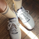 White sneakers with beige socks on a wooden floor