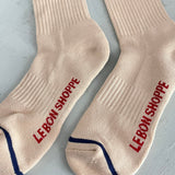 Beige socks with red text 'LEBON SHOPPE' on a light gray background