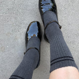 Black shiny shoes and gray socks on a gray pavement background