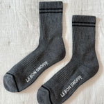 Pair of gray socks with 'Le Bon Shoppe' branding on a light wooden surface