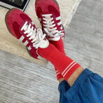 Red sneakers and socks with white laces on a neutral background