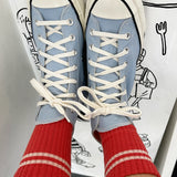 Blue high-top sneakers with white laces worn with red socks against a white background with black line art.