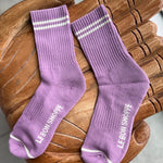 Pair of purple socks with white stripes on a wooden chair