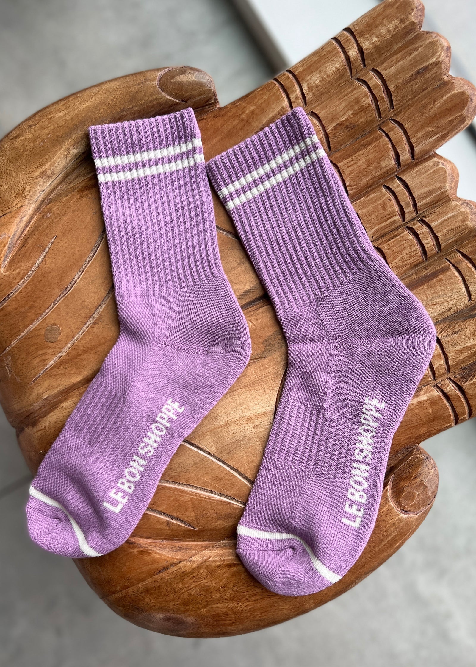 Pair of purple socks with white stripes on a wooden chair