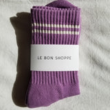 Purple socks with white stripes and a visible label on a gray fabric background