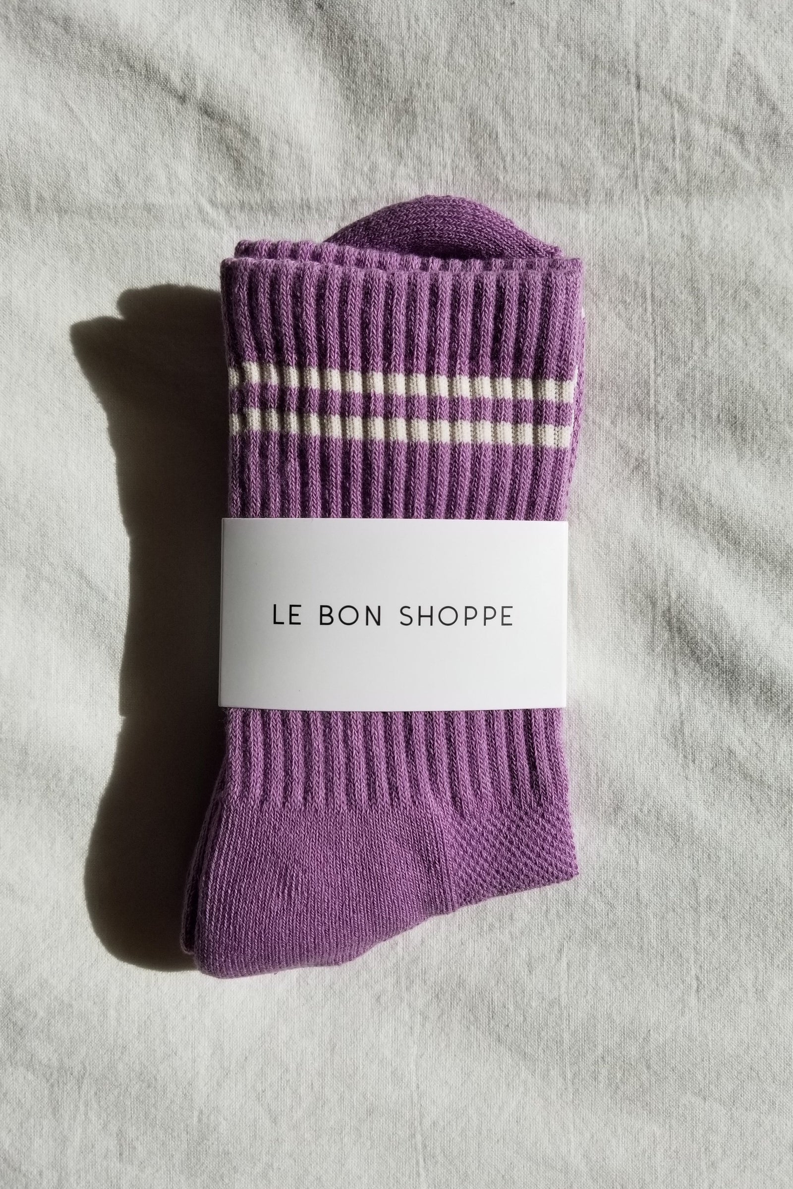Purple socks with white stripes and a visible label on a gray fabric background