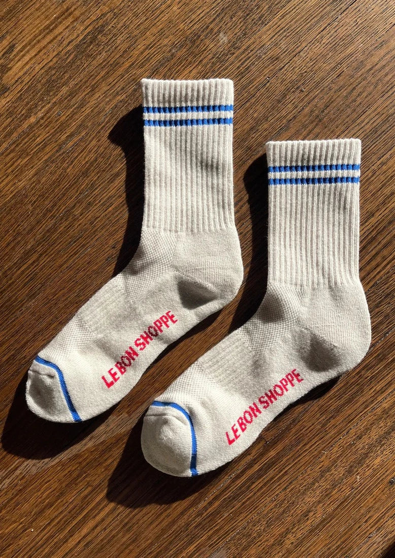 Oatmeal colored socks with blue stripes on a wood floor.
