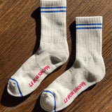 Oatmeal colored socks with blue stripes on a wood floor.