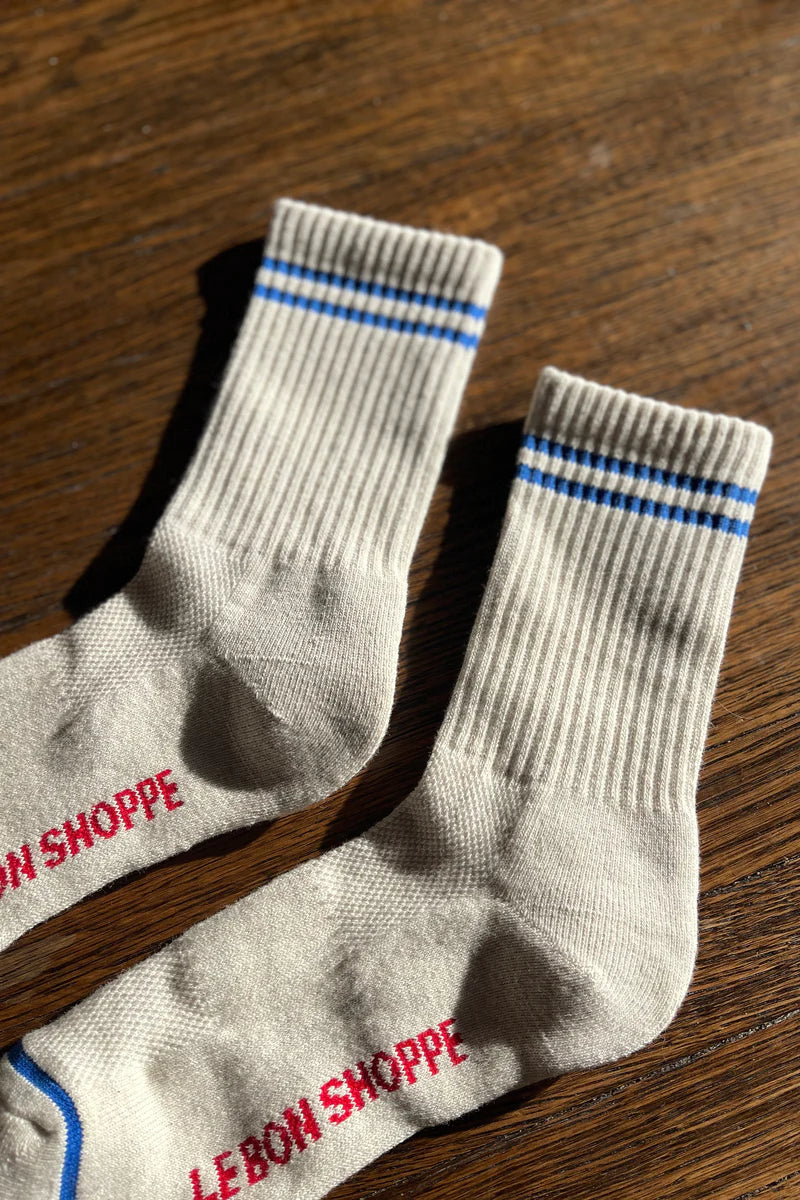 Oatmeal socks with blue stripes on a wood floor.