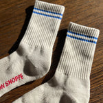 Oatmeal socks with blue stripes on a wood floor.