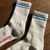 Oatmeal socks with blue stripes on a wood floor.