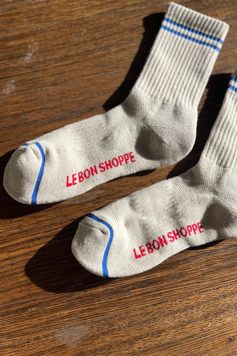 Oatmeal socks with blue stripes on a wood floor.
