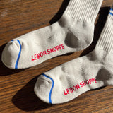 Oatmeal socks with blue stripes on a wood floor.