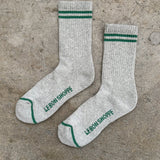 Gray socks with green stripes and 'Le Bon Shoppe' branding on a concrete surface
