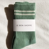 Green sock with white stripes and 'Le Bon Shoppe' label on a light background