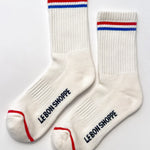 White socks with red and blue stripes and 'LEBON SHOPPE' branding on a light gray background