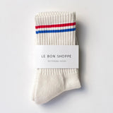 Beige socks with red and blue stripes on a white background, featuring 'Le Bon Shoppe' branding.