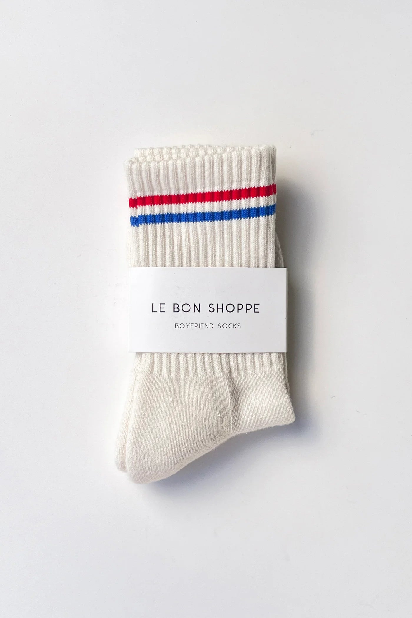 Beige socks with red and blue stripes on a white background, featuring 'Le Bon Shoppe' branding.