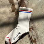 White sock with red and blue stripes on a concrete surface