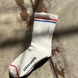 White sock with red and blue stripes on a concrete surface