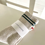 Cream color socks with green stripes in Le Bon Shoppe packaging.