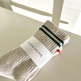 Cream color socks with green stripes in Le Bon Shoppe packaging.