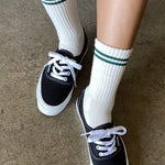 White socks with green stripes worn with black sneakers.
