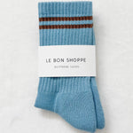 Powder blue socks with brown stripes in Le Bon Shoppe packaging on a white background.