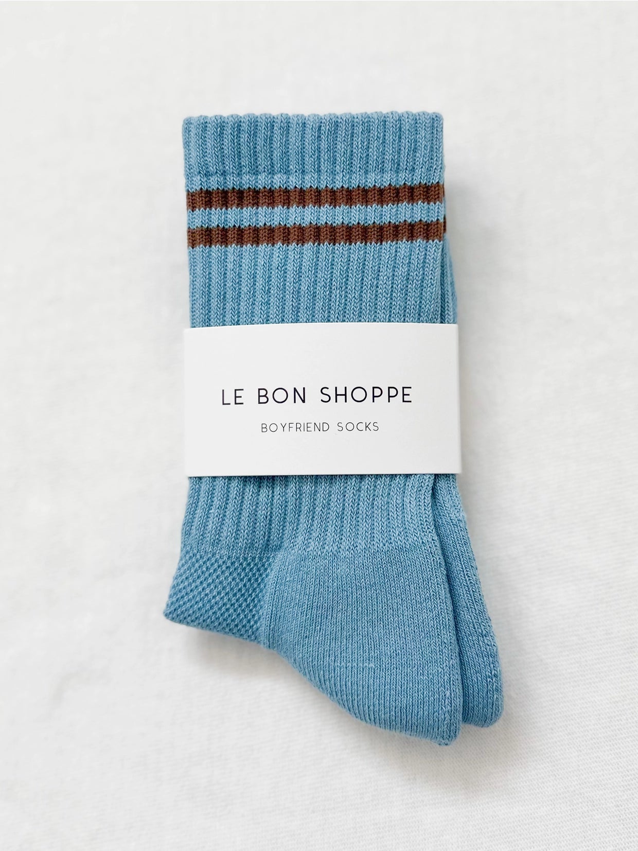 Powder blue socks with brown stripes in Le Bon Shoppe packaging on a white background.