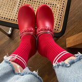 Red shoes and socks with light blue jeans on a wooden floor.