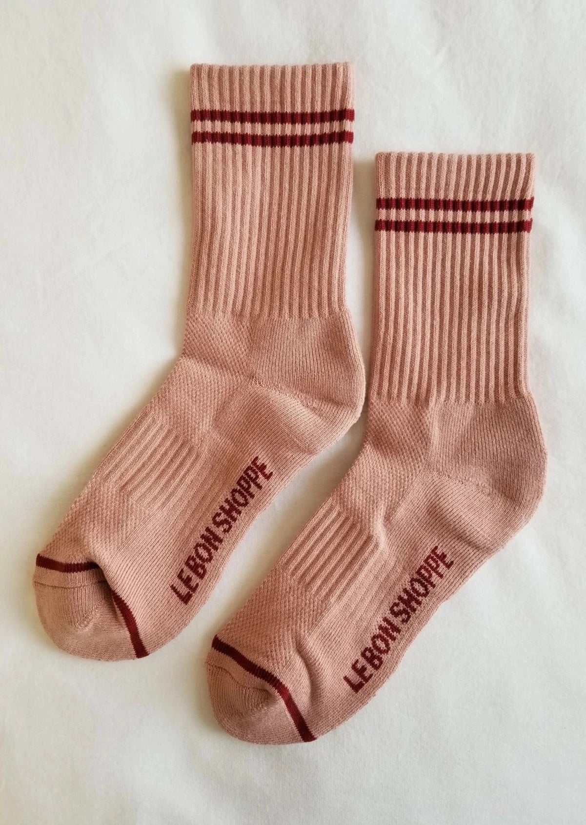Pink socks with red stripes on white background.