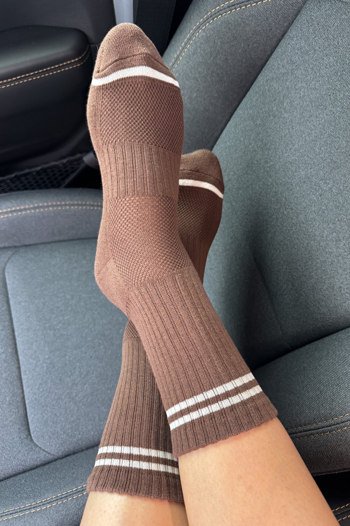 Brown socks with white stripes on a car seat