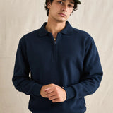 Man wearing a navy blue sweater and green cap against a beige background