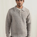 Man wearing a gray knitted sweater against a plain background
