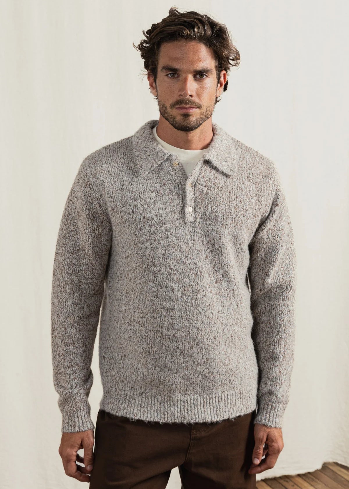 Man wearing a gray knitted sweater against a plain background