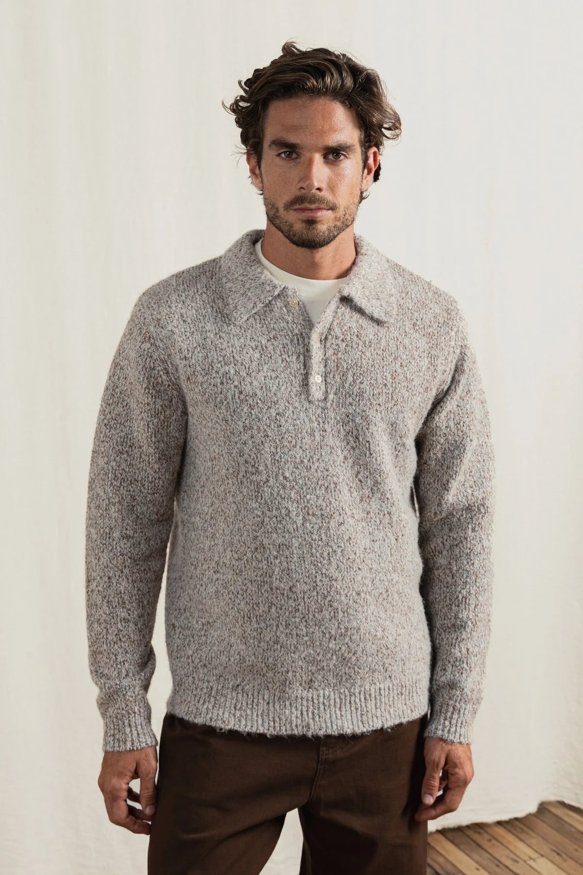 Man wearing a gray knitted sweater against a plain background