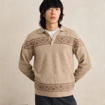 Man wearing a beige knitted sweater with patterned details against a plain background