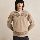 Man wearing a beige knitted sweater with patterned details against a plain background
