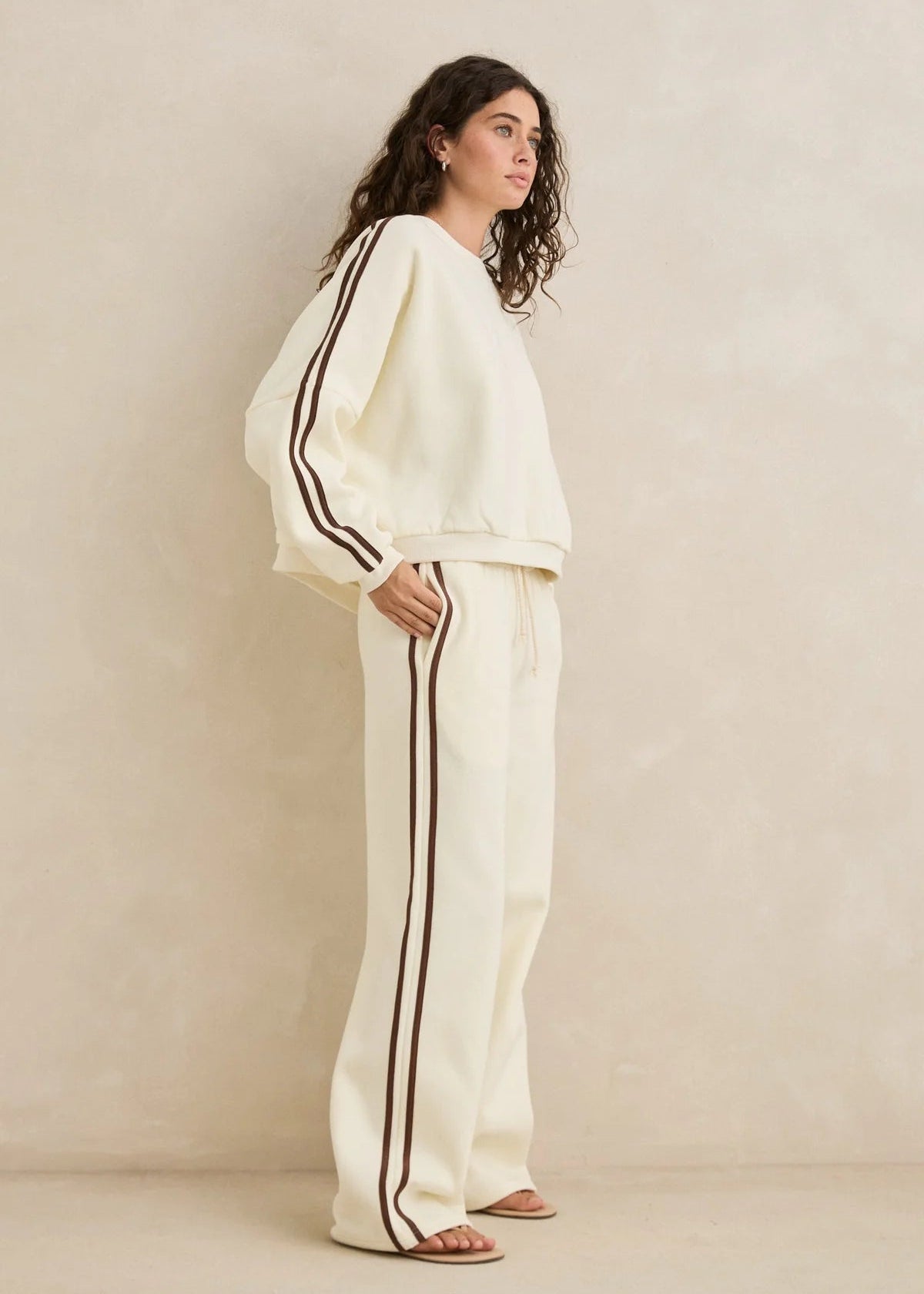 Woman wearing a white outfit with black stripes against a beige background