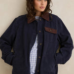 Woman wearing a navy jacket with brown accents against a beige background