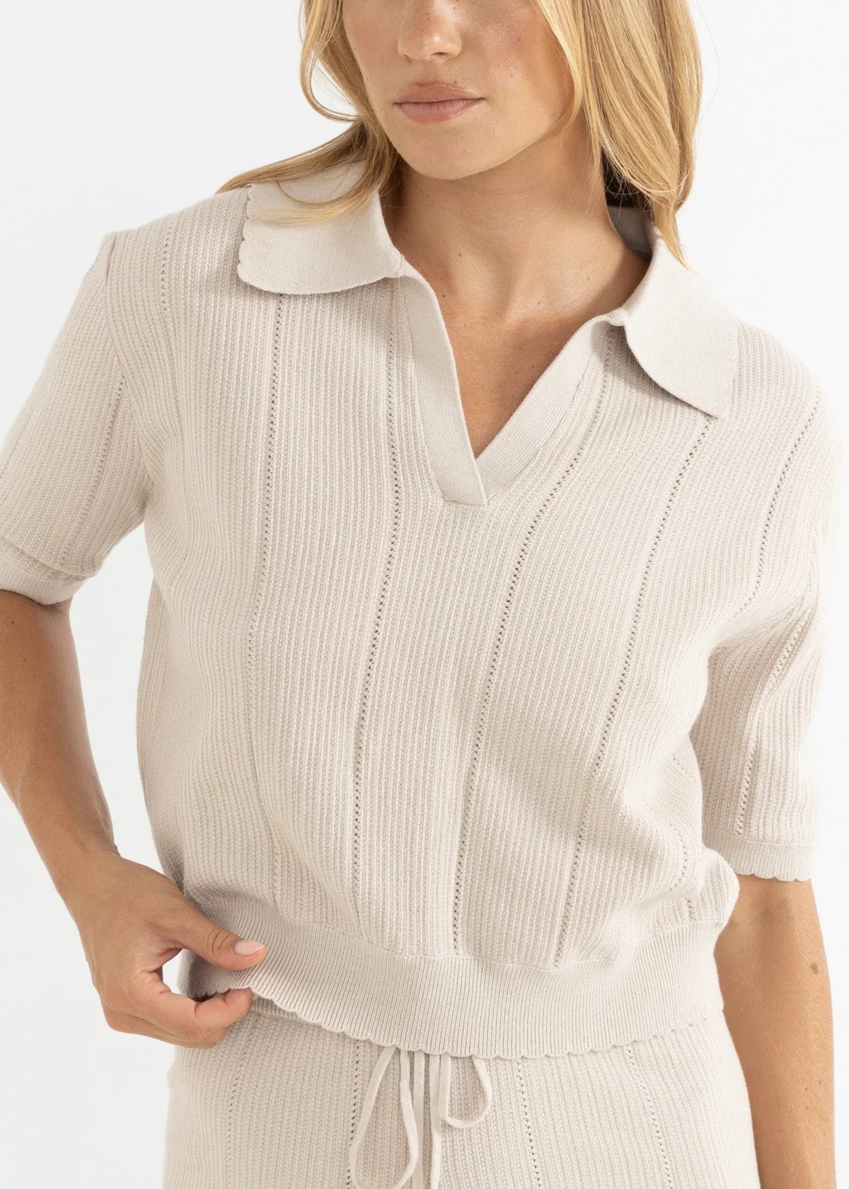 Woman wearing a beige ribbed dress with a belt on a white background