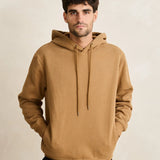 Man wearing a brown hoodie against a beige background