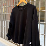 Black sweatshirt on a wooden hanger against a metal grid background