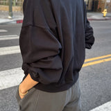 Person wearing a black sweatshirt and gray pants on a city street.