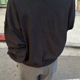 Person wearing a black sweatshirt and light gray pants on a street.