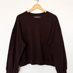 Brown sweatshirt on a wooden hanger against a white background