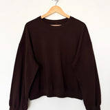 Brown sweatshirt on a wooden hanger against a white background