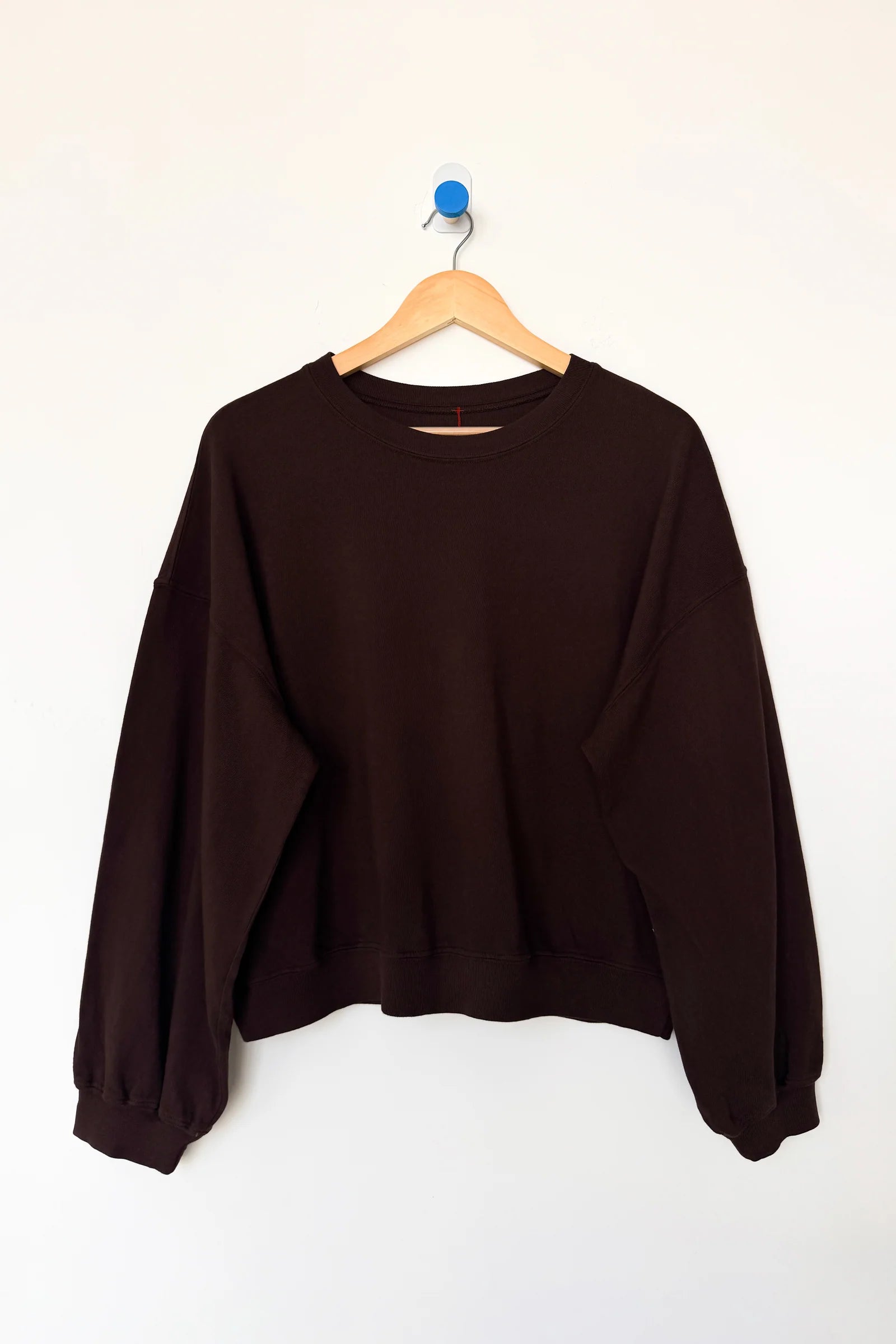 Brown sweatshirt on a wooden hanger against a white background