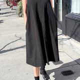 Person wearing a black sleeveless dress on a street.