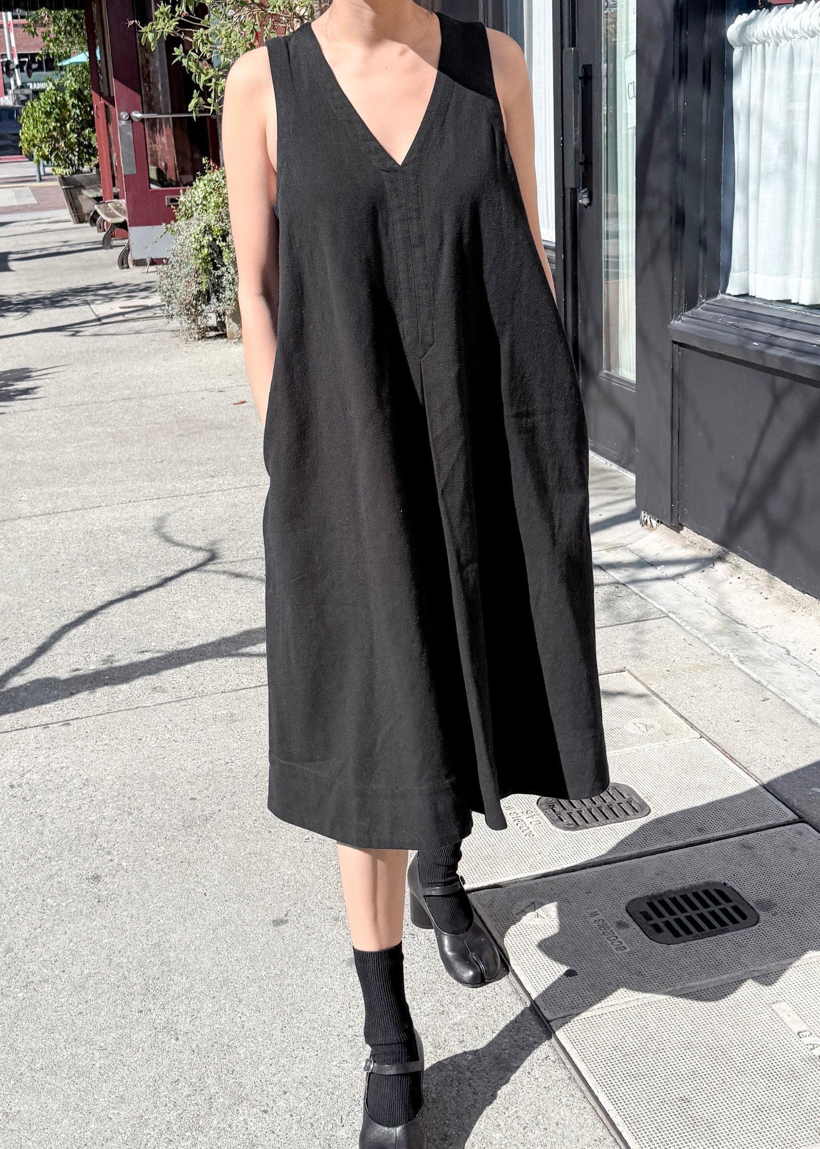 Person wearing a black sleeveless dress on a street.